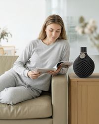 Frau ließt gemütlich eine Zeitschrift, daneben steht die Vase Velo auf einem Tisch