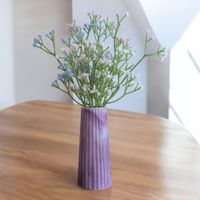 pink design ribbed resin vase which tapers at the top, there are artificial flowers inside