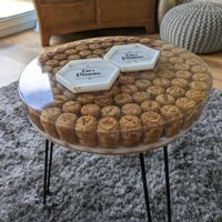A round side table created from resin with a prosecco cork design and metal pin style legs, set in a cosy home