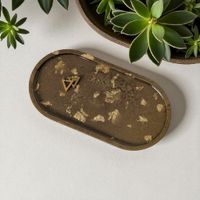 gold resin trinket tray with gold fleck design, resting on a white background.
