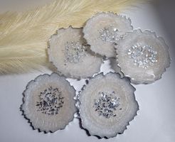 5 geode style resin coaters, with a silver and opaque pearl effect design, resting on a white background