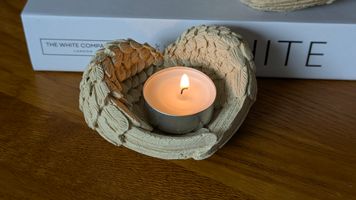 Feather design tea light holder in beige resting on a wooden table