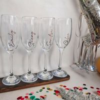 four prosecco flutes personalised with names resting on a table top